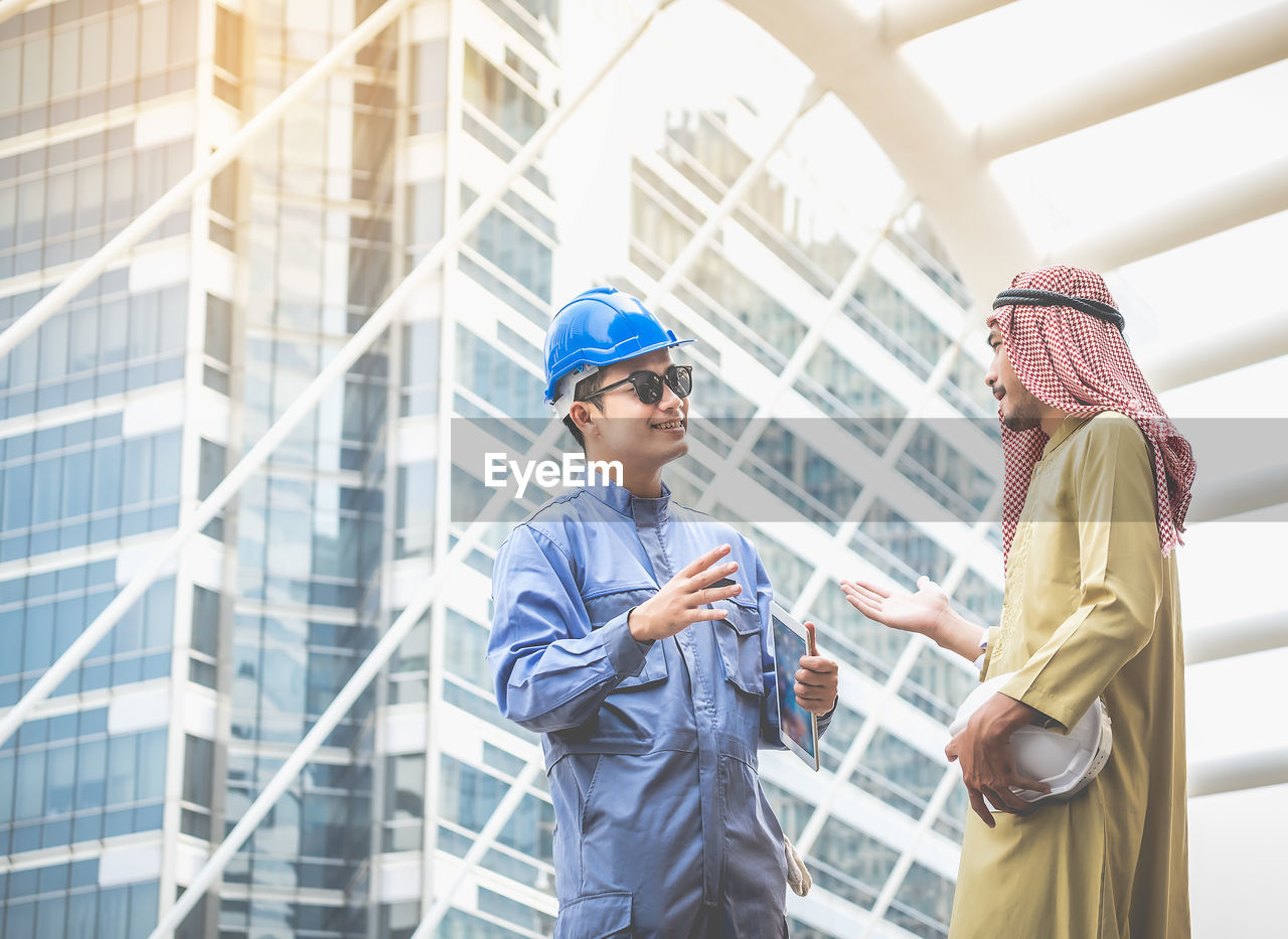 Engineer talking to colleague against modern building