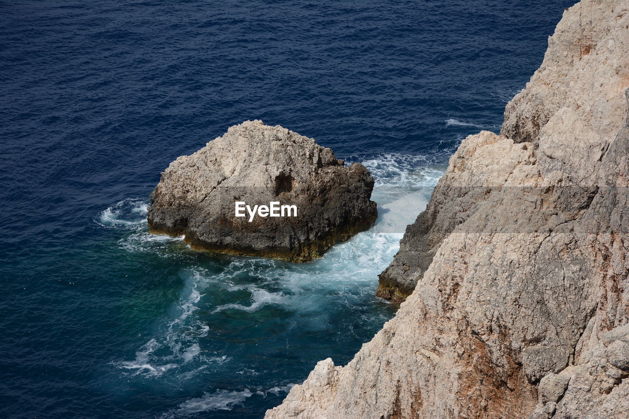 HIGH ANGLE VIEW OF ROCK FORMATIONS BY SEA