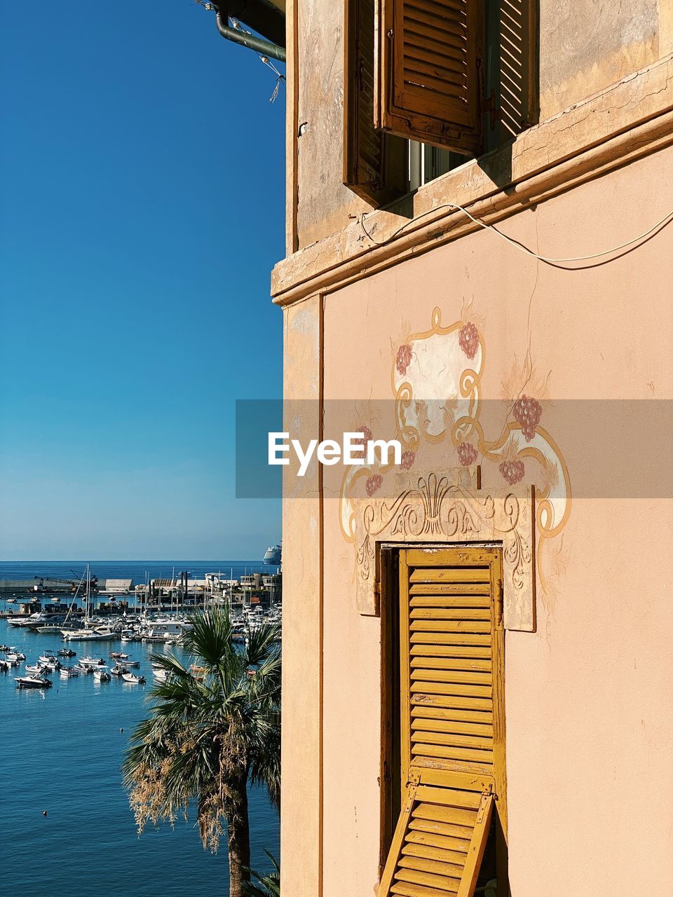 Low angle view of building with windows against clear blue sky and blue sea 