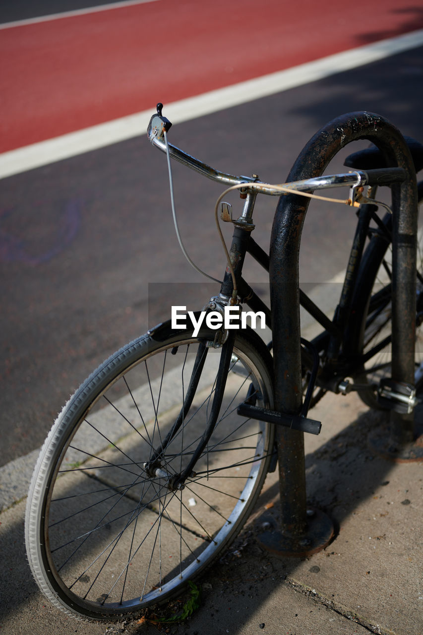 Bicycle locked to a pole on a sunny day