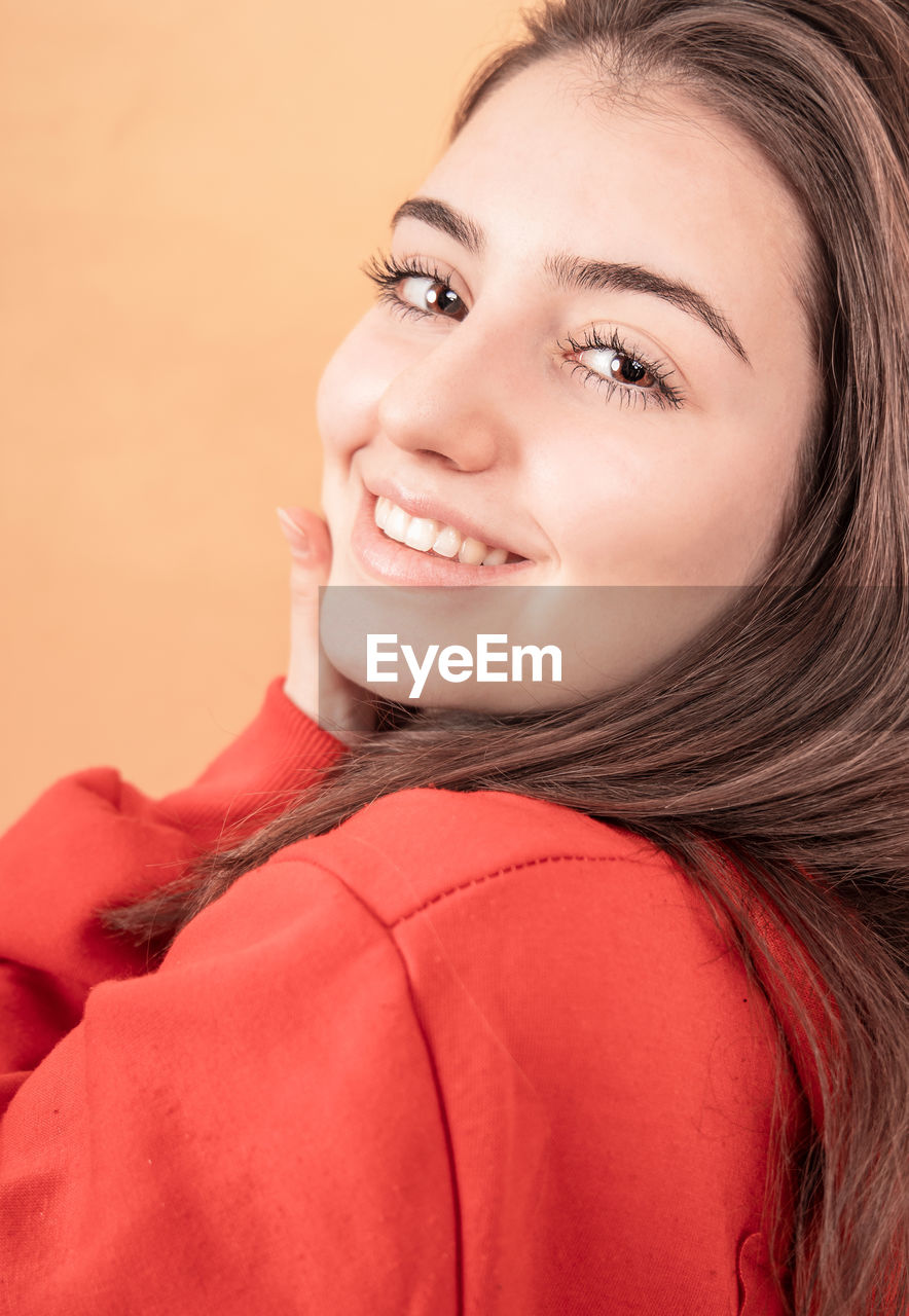 PORTRAIT OF A SMILING YOUNG WOMAN OVER GRAY BACKGROUND