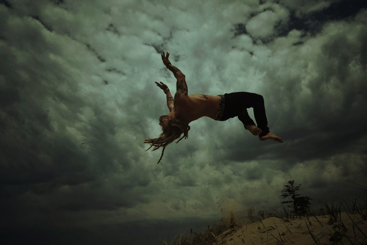 LOW ANGLE VIEW OF WOMAN JUMPING IN SKY