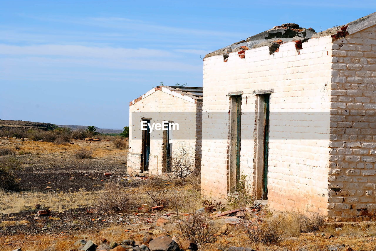 architecture, built structure, ruins, building exterior, history, sky, ancient history, building, nature, the past, abandoned, no people, old, rural area, landscape, land, day, wall, fortification, house, old ruin, outdoors, rundown, ruined, rural scene, sunlight, blue, sunny, door, weathered, travel destinations, entrance, travel, damaged, brick, clear sky