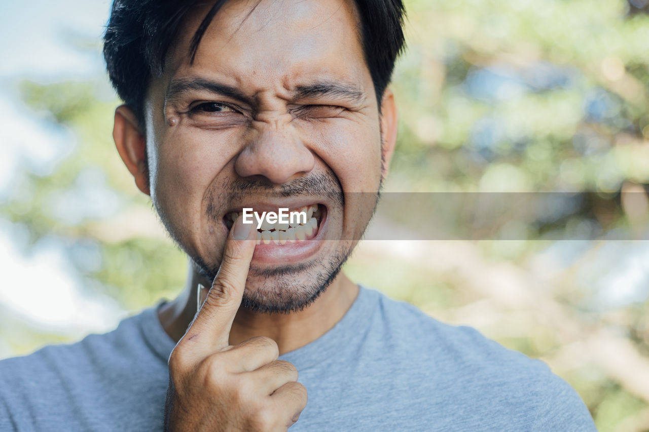 Close-up of man looking away while touching teeth in pain