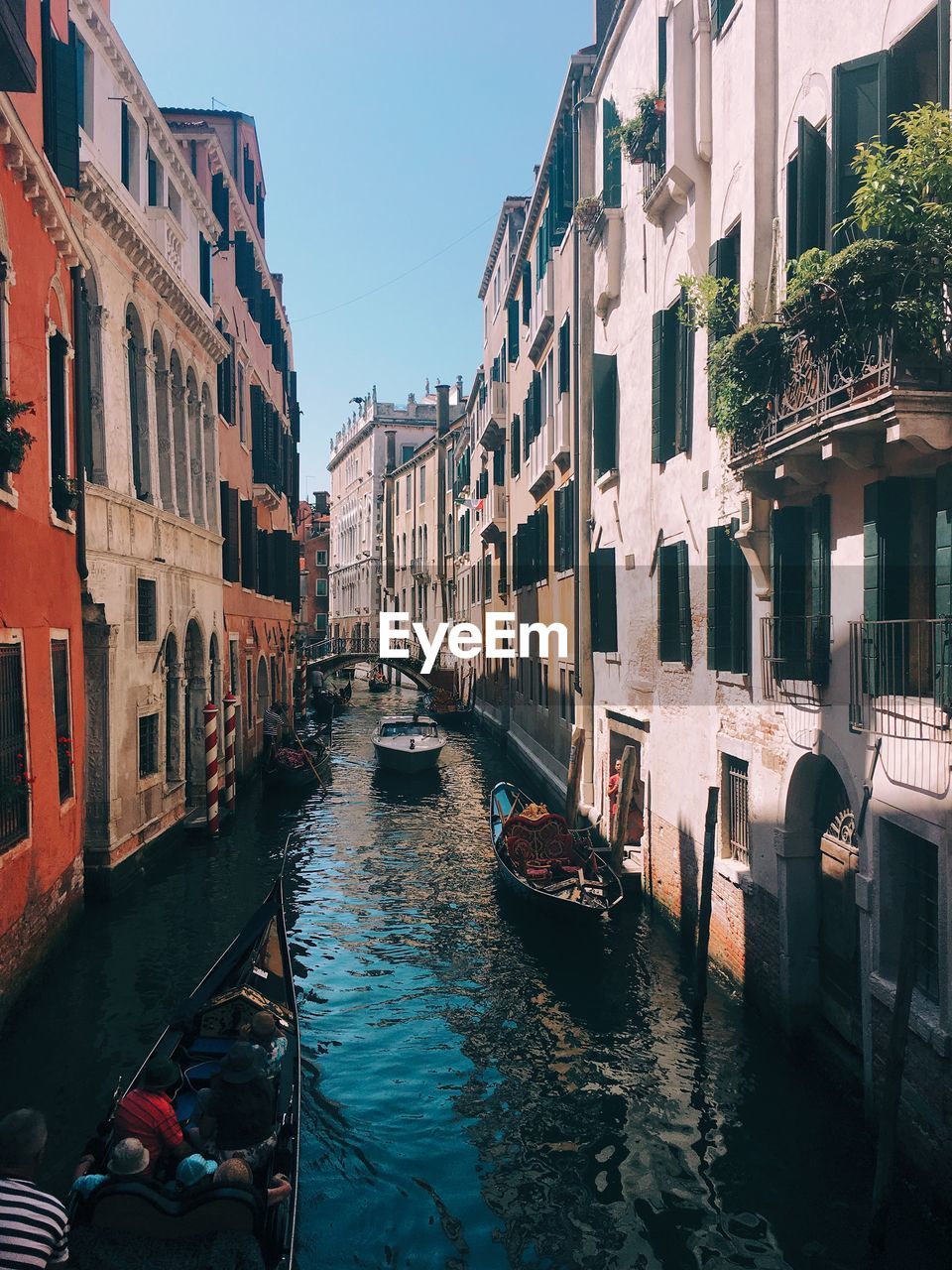 BOATS MOORED IN CANAL AMIDST BUILDINGS AGAINST SKY