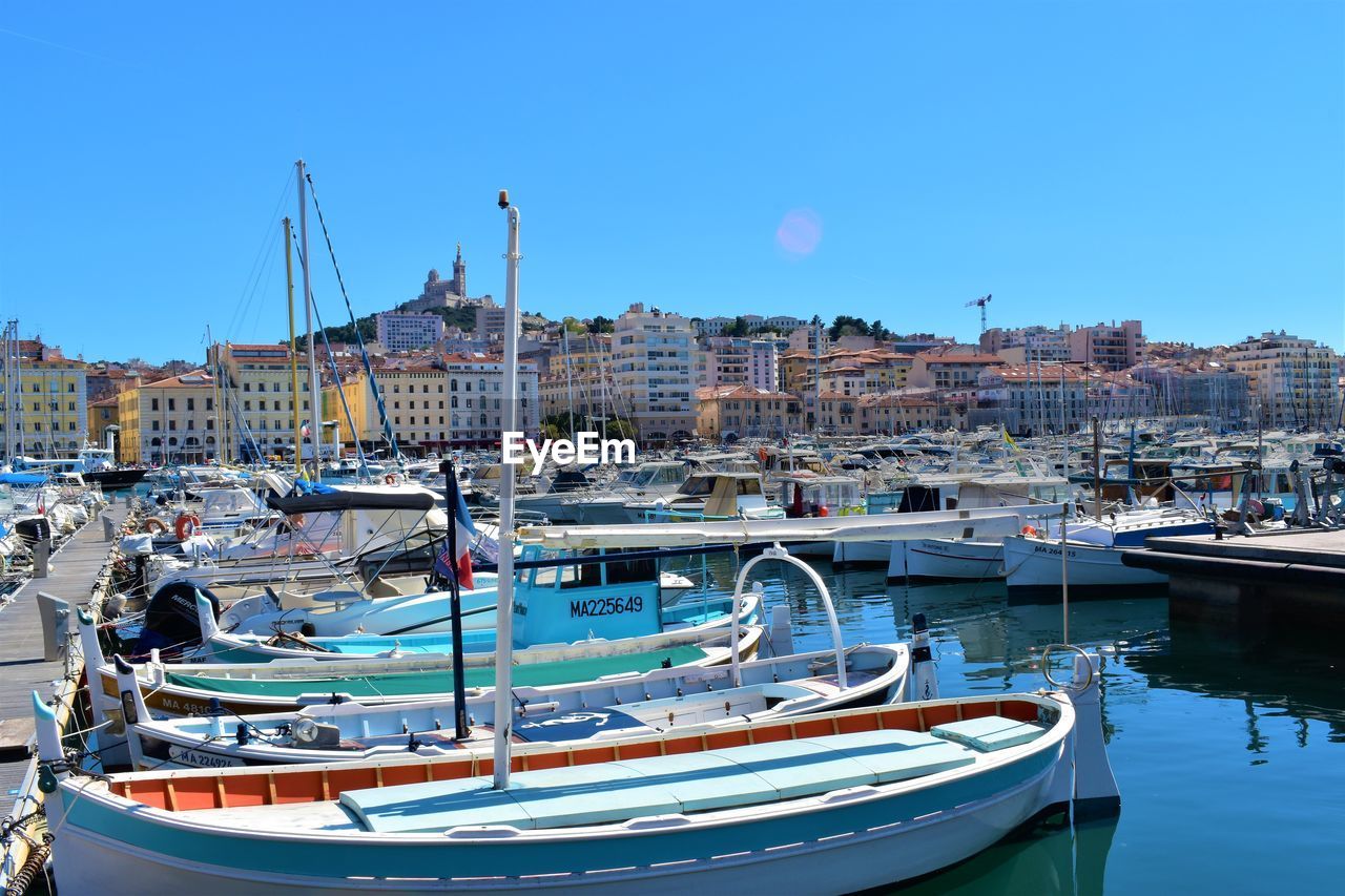 BOATS MOORED AT HARBOR AGAINST BUILDINGS IN CITY