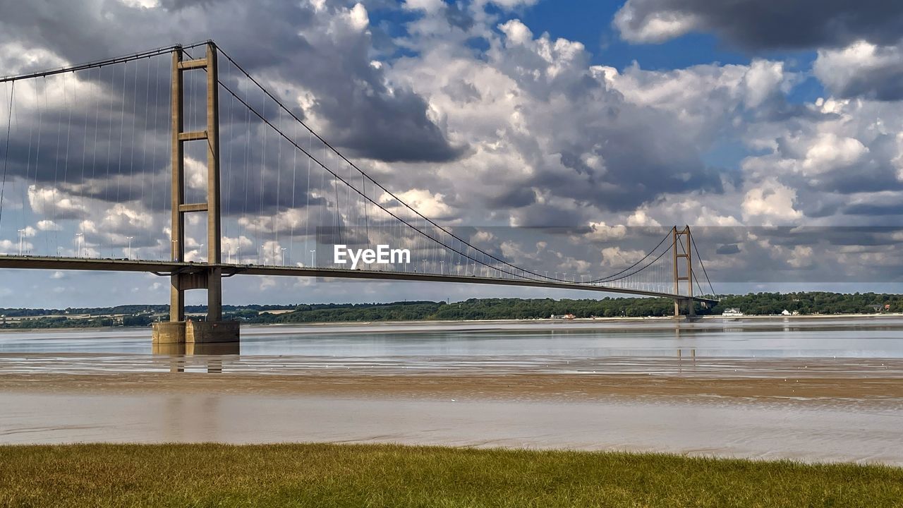 water, sky, cloud, bridge, architecture, built structure, nature, travel destinations, transportation, sea, suspension bridge, travel, tourism, landscape, environment, beauty in nature, scenics - nature, land, city, horizon, cable-stayed bridge, beach, shore, dramatic sky, reflection, no people, tranquility, cloudscape, urban skyline, outdoors, tranquil scene, bay of water, bay, cityscape, holiday, panoramic, coastline, trip, day, water's edge, vacation, building exterior, sunlight, road, idyllic, summer, atmospheric mood, building, overcast, low tide, business finance and industry, moody sky, blue, street, cable