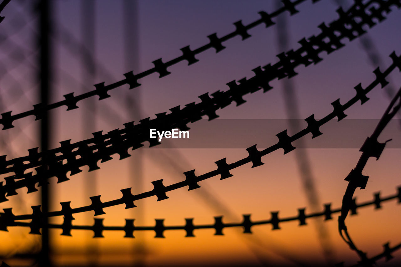 Low angle view of barbed wire against sky at dusk