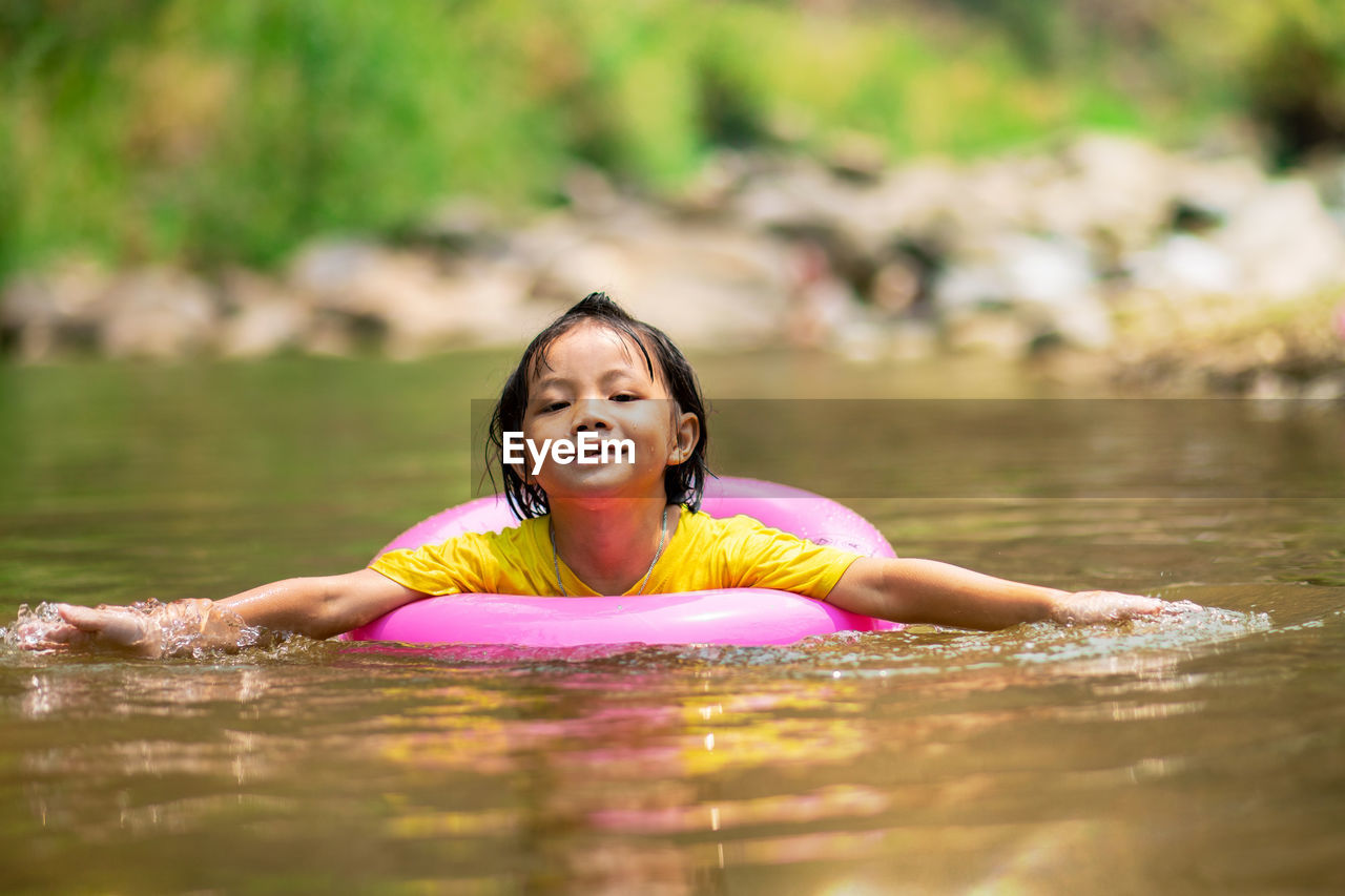 Portrait of girl with inflatable ring swimming in river