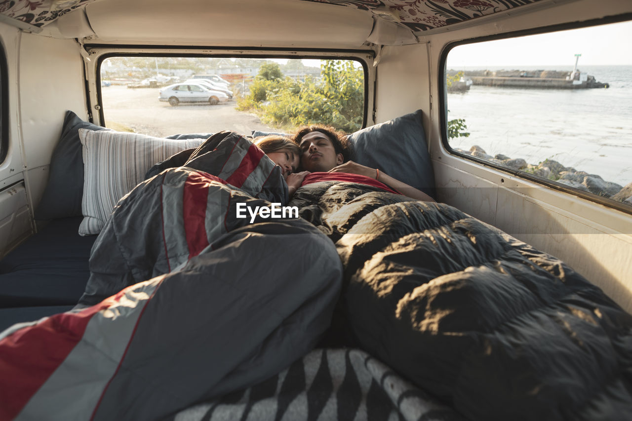 Young couple resting in camping van by seashore