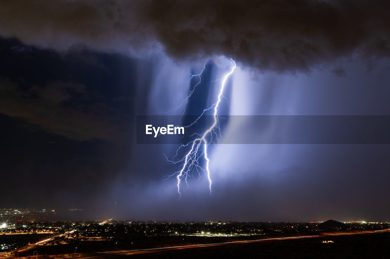 A dramatic lightning bolt strikes through a microburst in a storm over phoenix, arizona