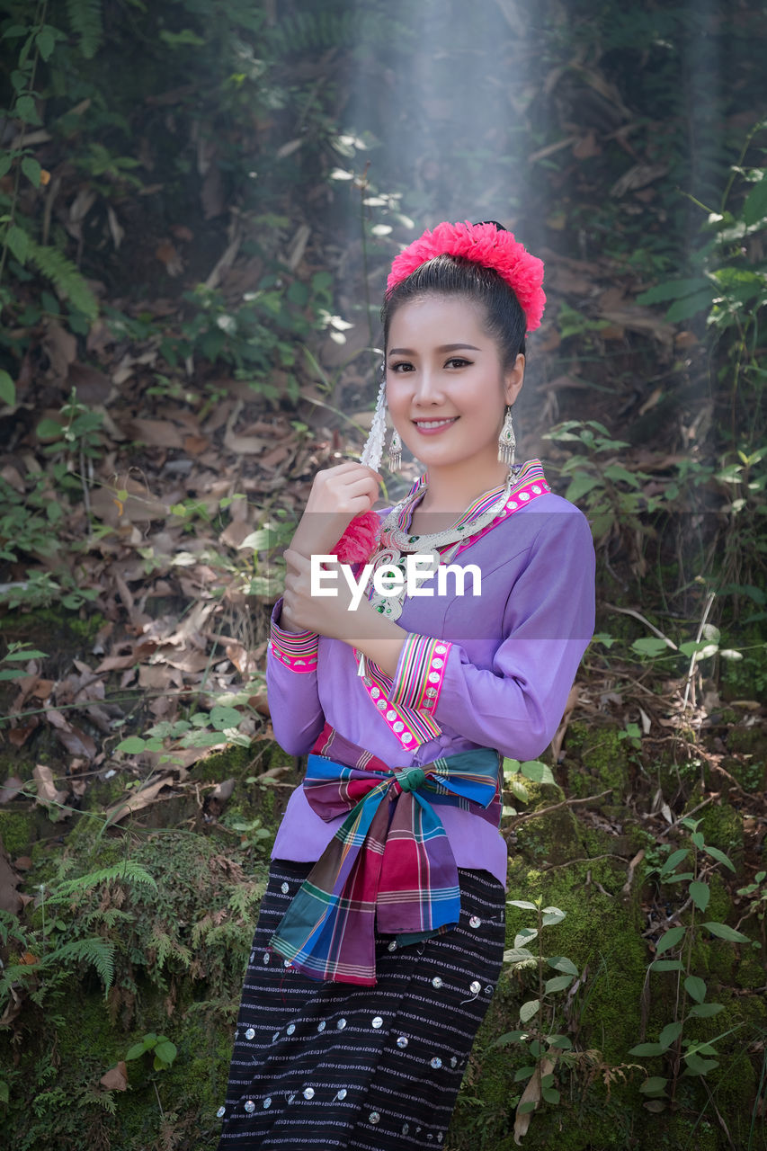 Portrait of smiling young woman standing in forest