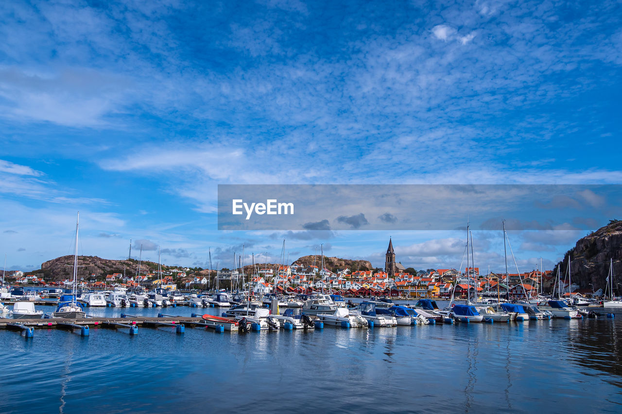 SAILBOATS MOORED IN HARBOR AGAINST SKY