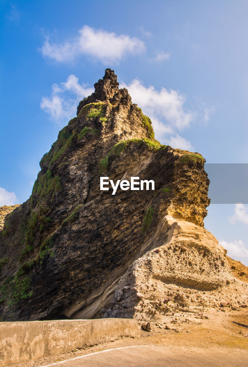 Low angle view of rock formation on mountain against sky
