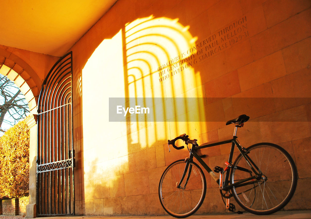 Low angle view of bicycle against wall on sunny day