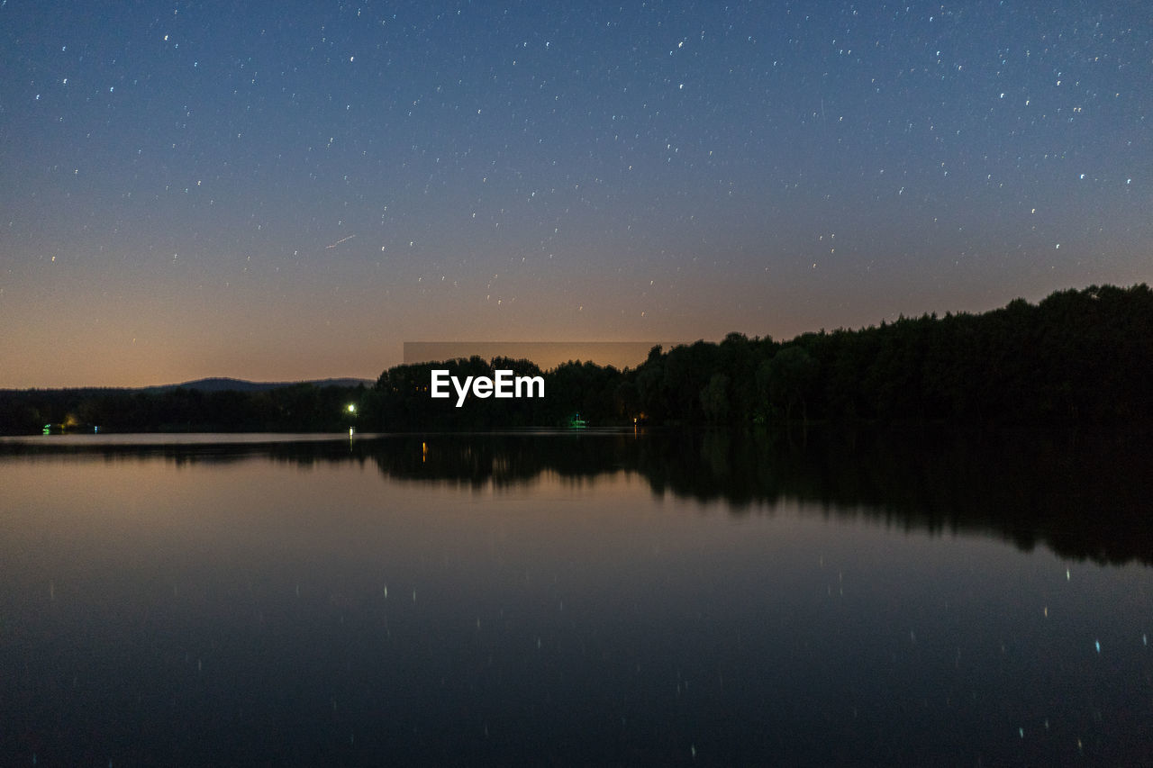 Scenic view of lake against clear sky at night