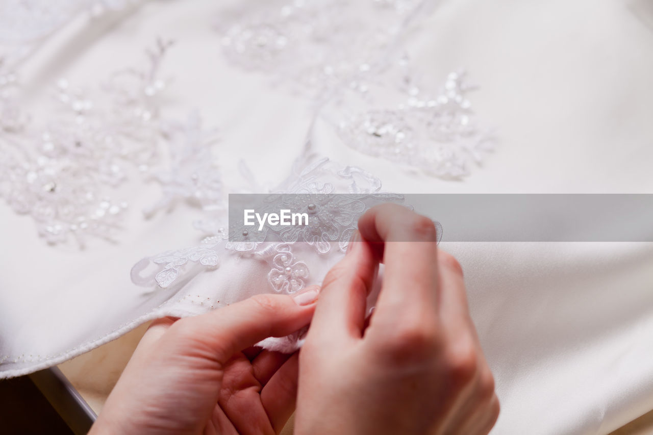 Cropped hands of woman stitching wedding dress