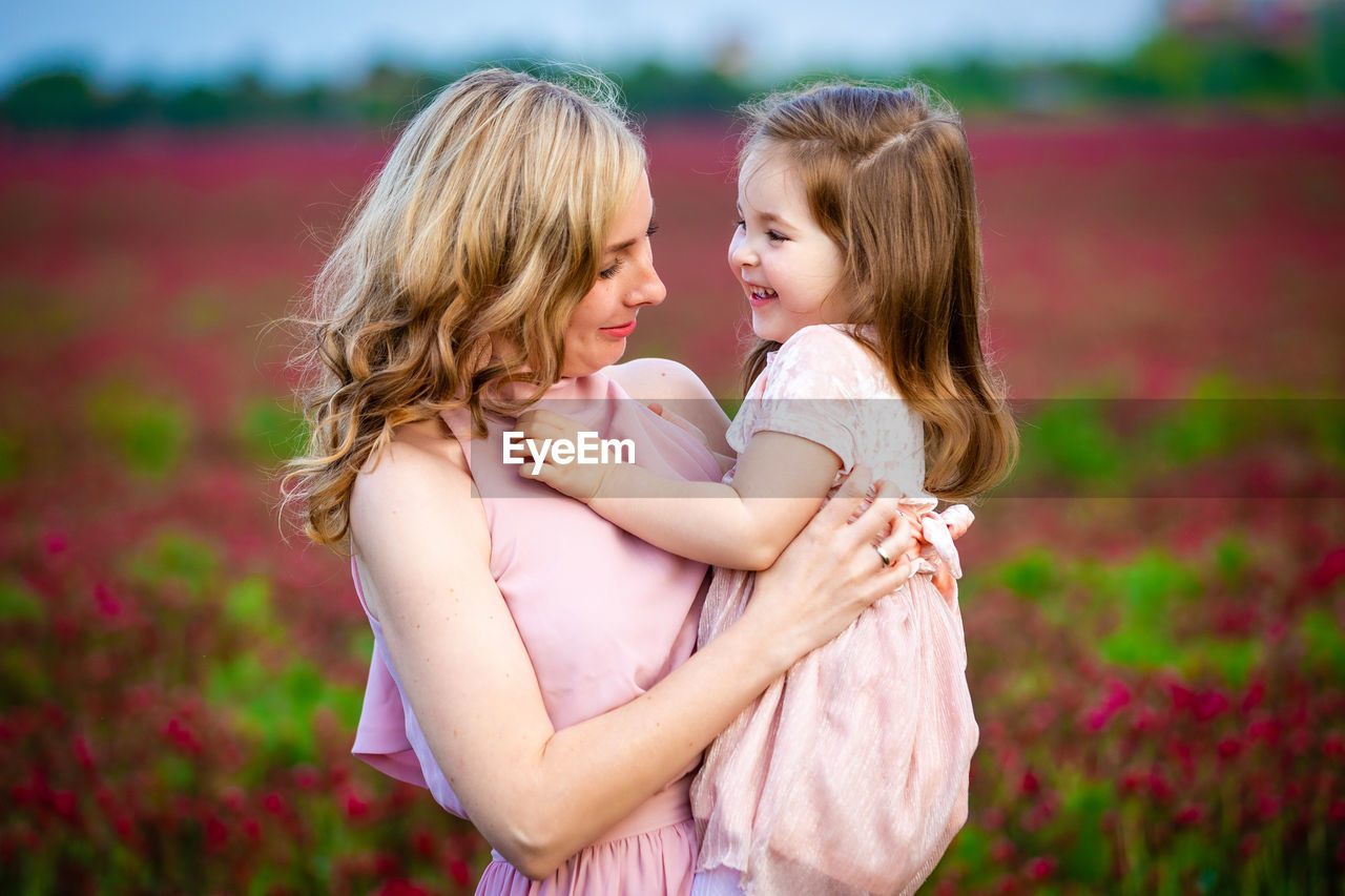 Smiling woman with daughter standing in farm