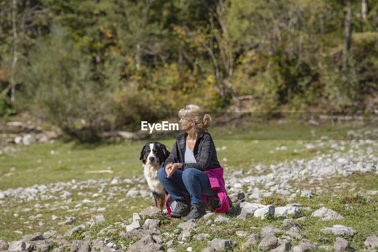 Rear view of woman with dog sitting outdoors