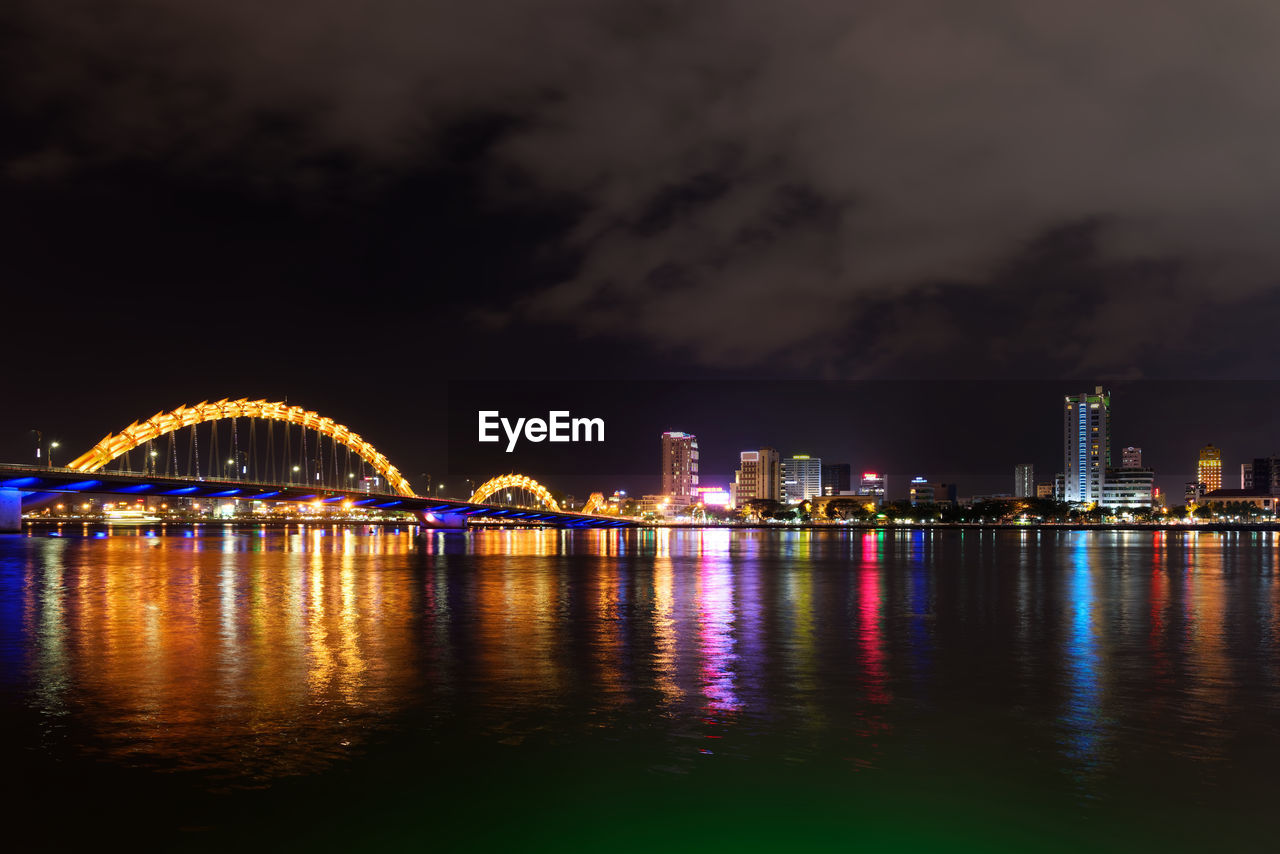 Illuminated dragon bridge and da nang city by han river, vietnam