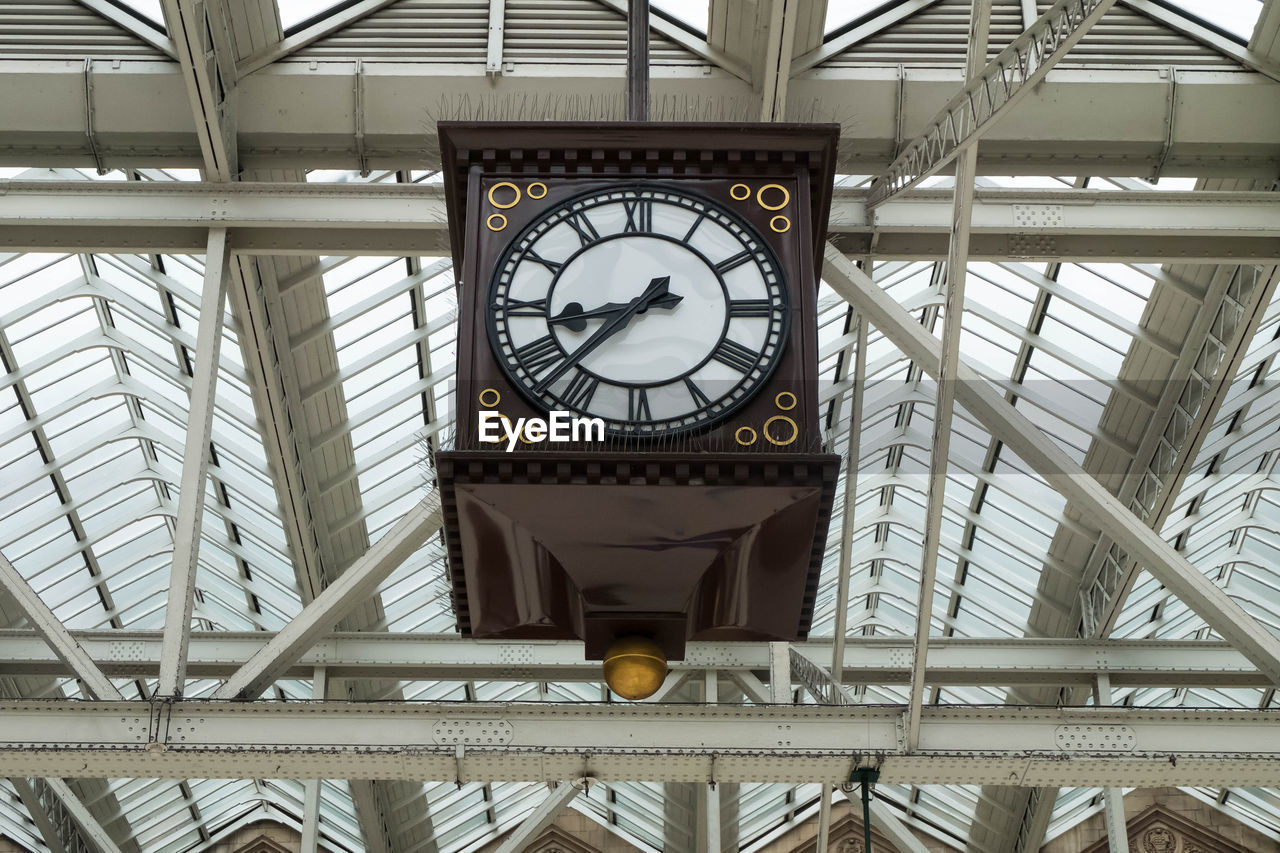 LOW ANGLE VIEW OF CLOCK ON CEILING IN UNDERGROUND