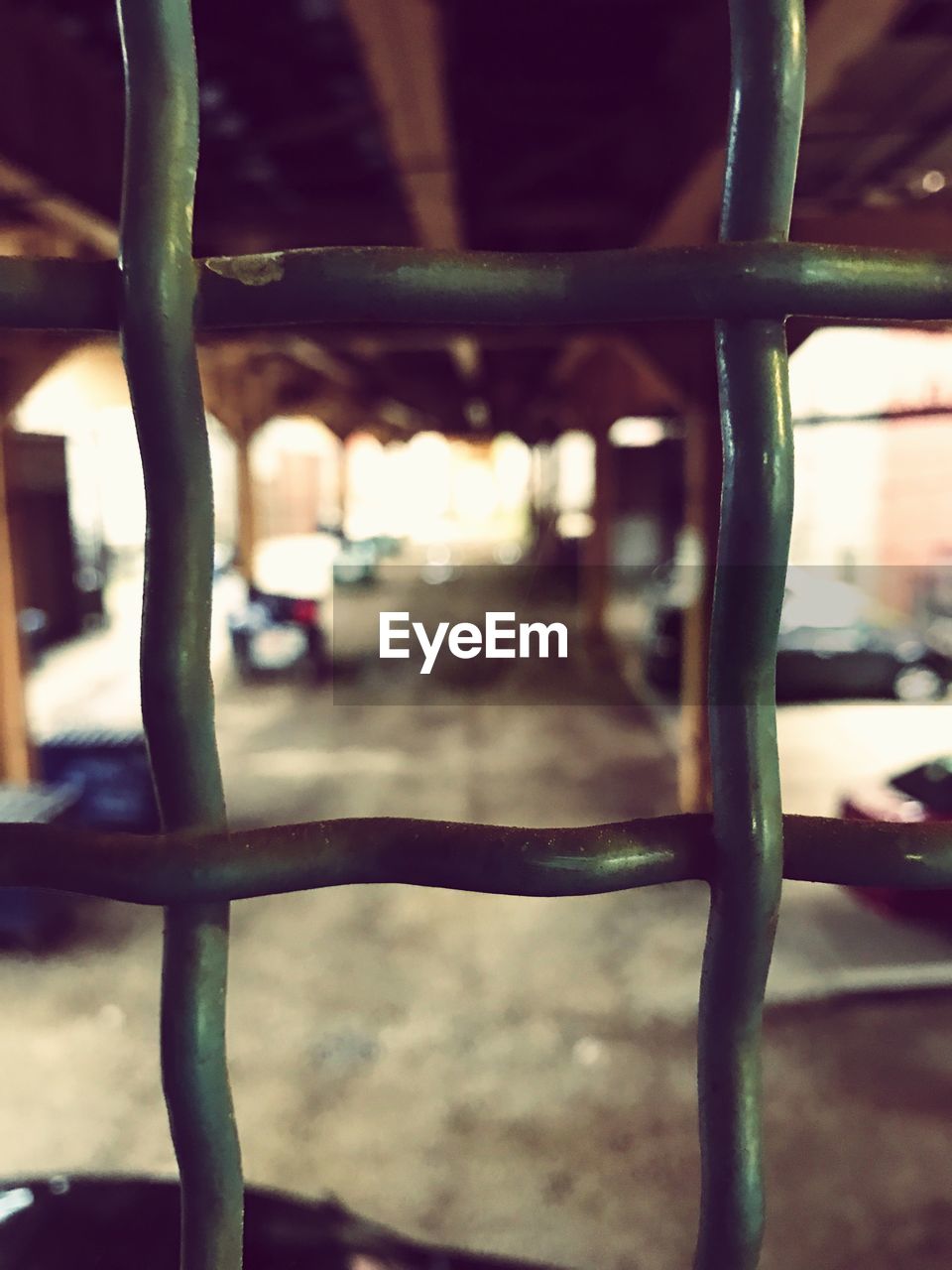 METAL FENCE AGAINST BLURRED BACKGROUND SEEN THROUGH METALLIC RAILING AT RAILROAD TRACK