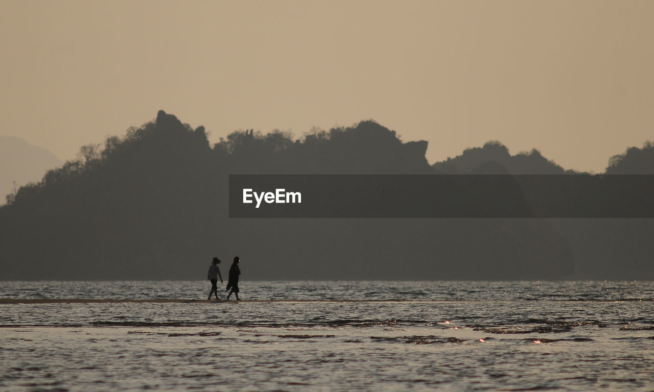 SILHOUETTE PEOPLE AT BEACH AGAINST CLEAR SKY