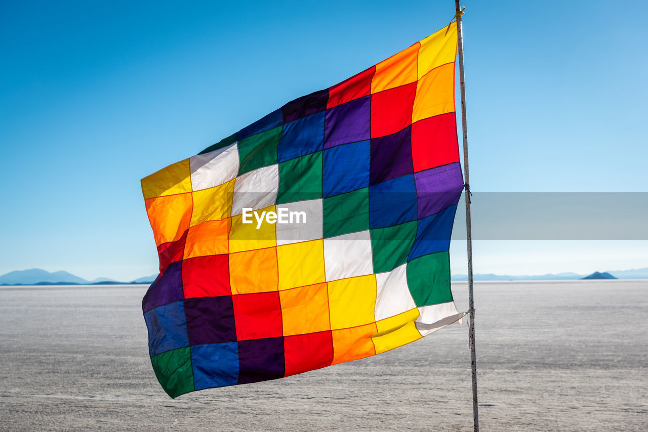 MULTI COLORED FLAG AGAINST CLEAR SKY