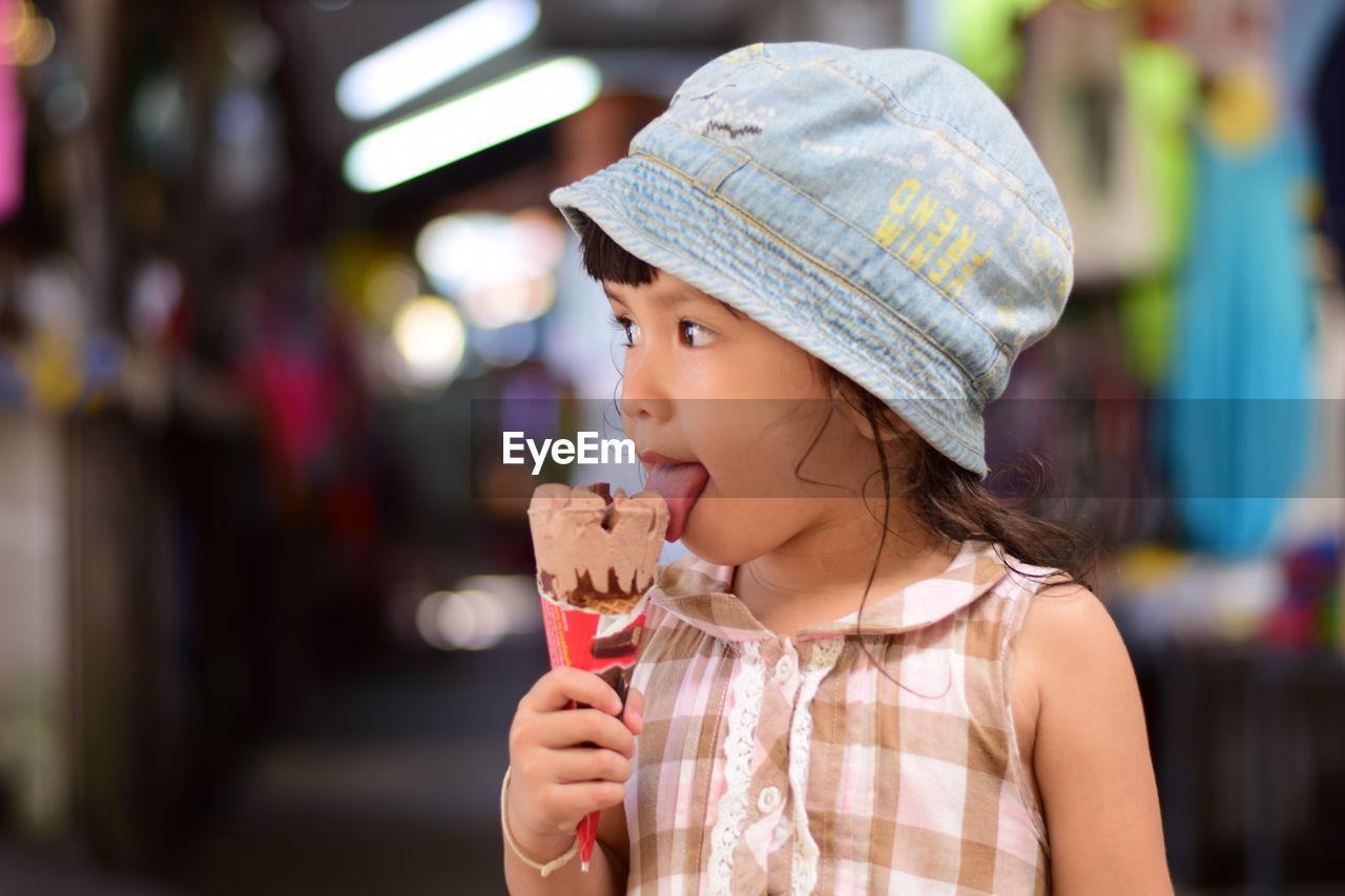 Close-up of girl eating ice cream cone while standing outdoors