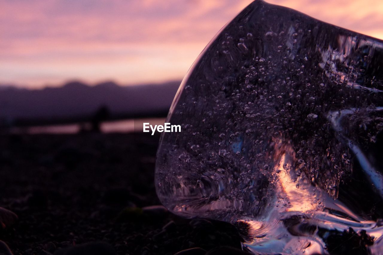 Close-up of ice on shore during sunset