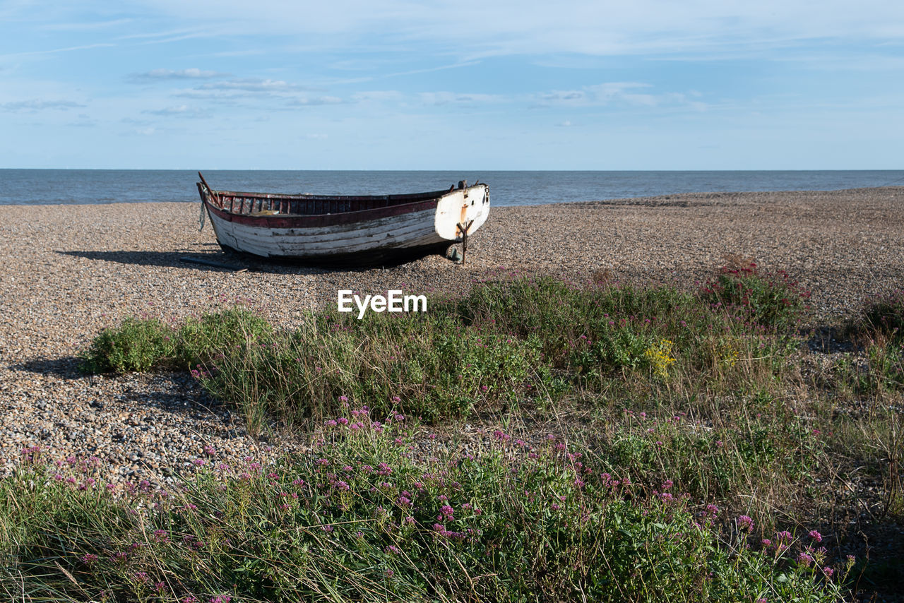 BOAT MOORED ON SHORE AGAINST SEA