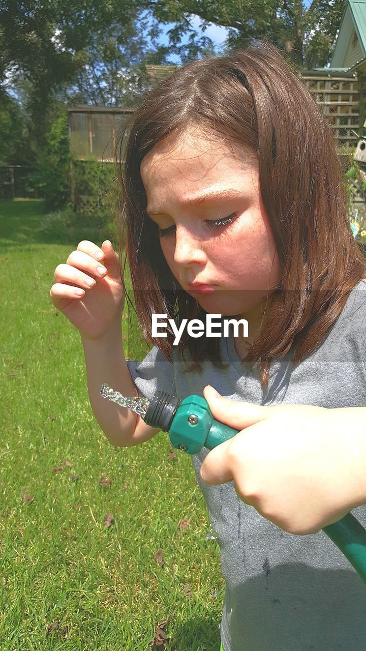 Girl holding garden hose in lawn