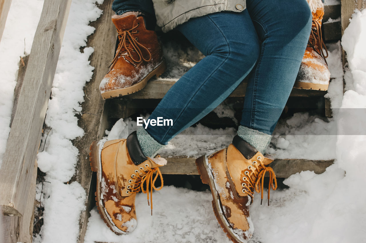 Low section of couple sitting on steps during winter