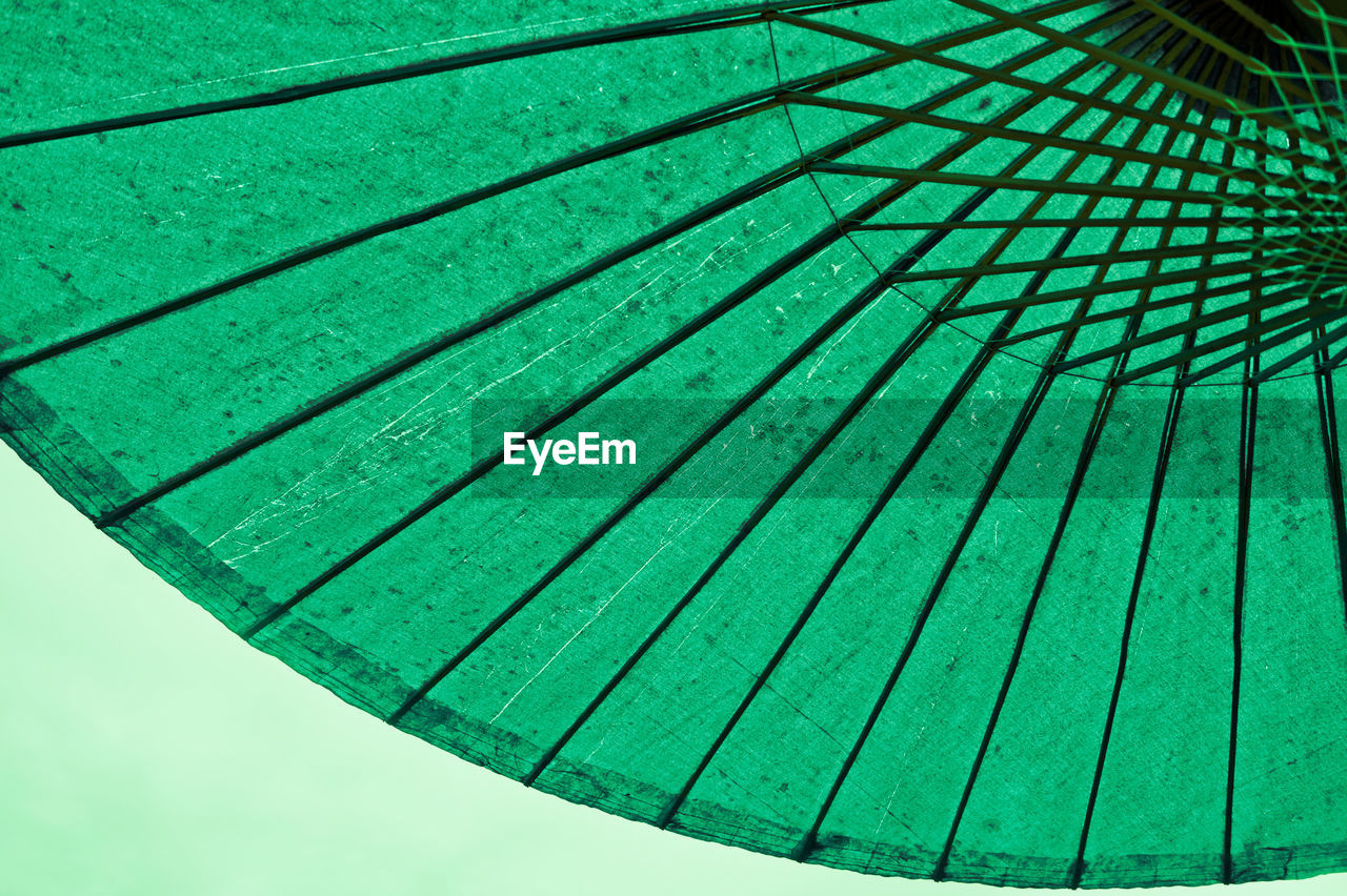 Low angle view of parasol against green background