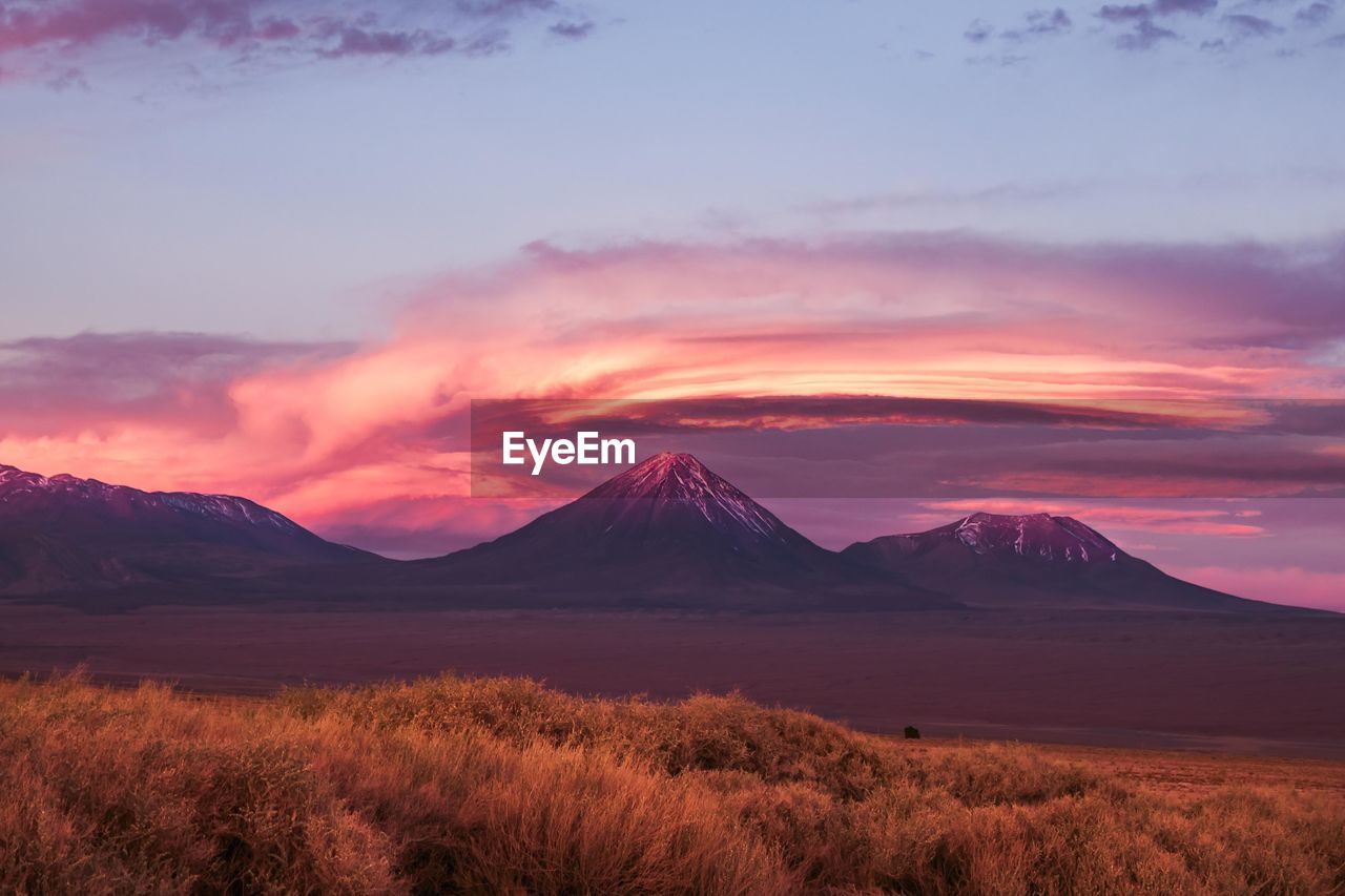 Scenic view of lake and mountains against cloudy sky during sunset