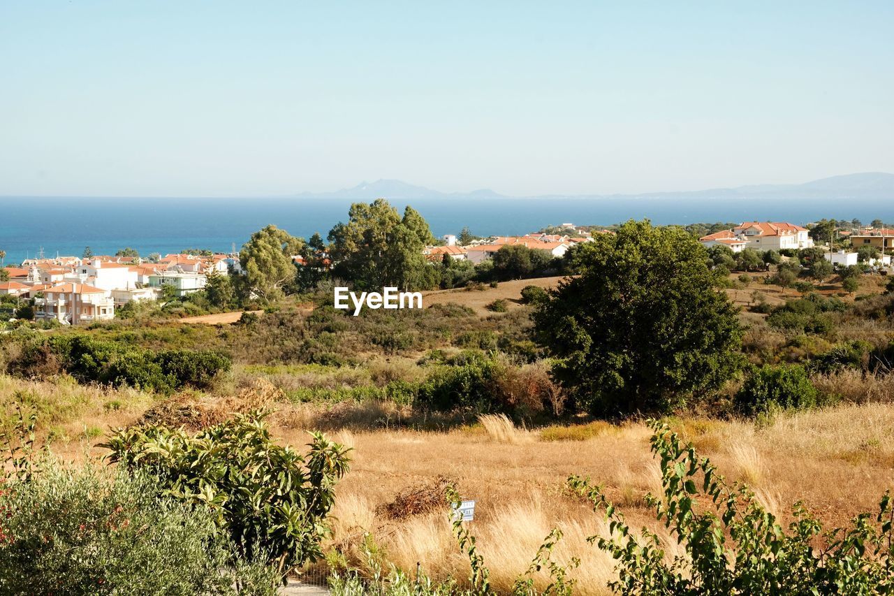 Scenic view of landscape by sea against clear sky