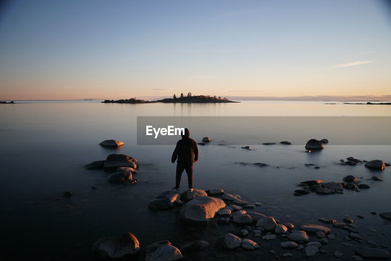 Rear view of people at beach during sunset