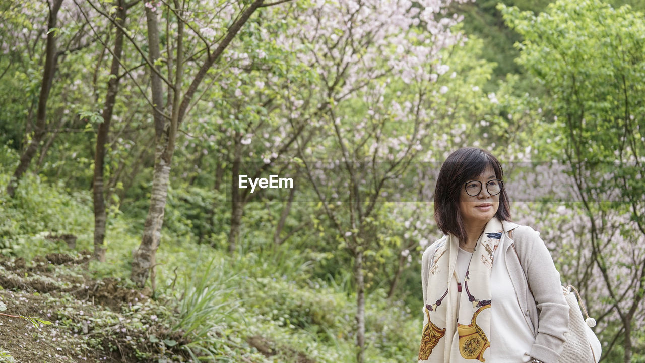 Young woman looking away while standing on land