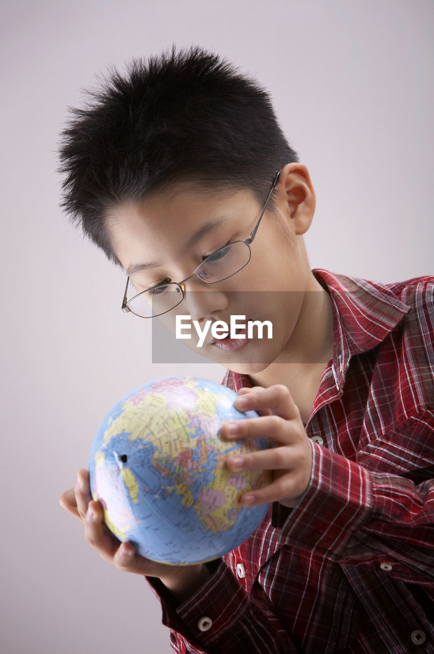 Boy holding globe against white background