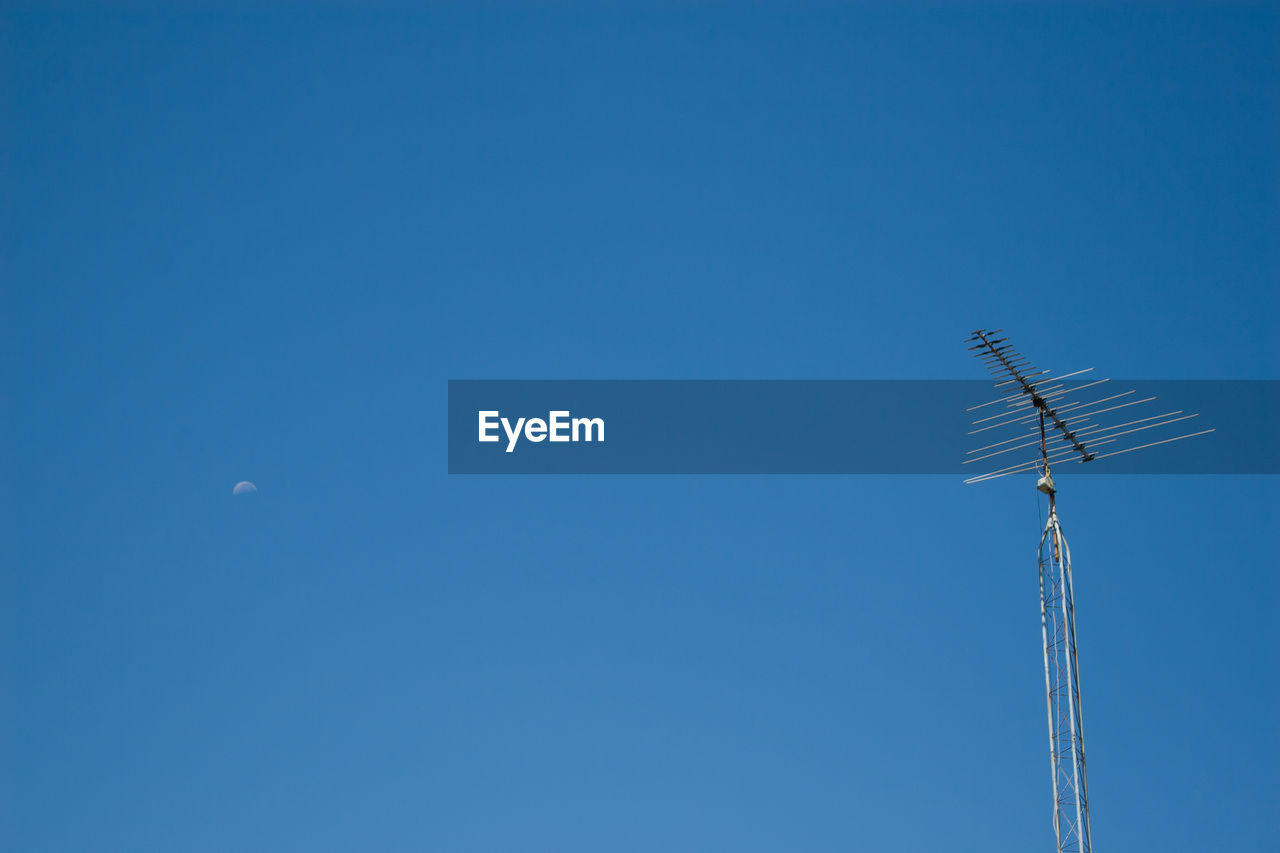 Low angle view of antenna against clear blue sky