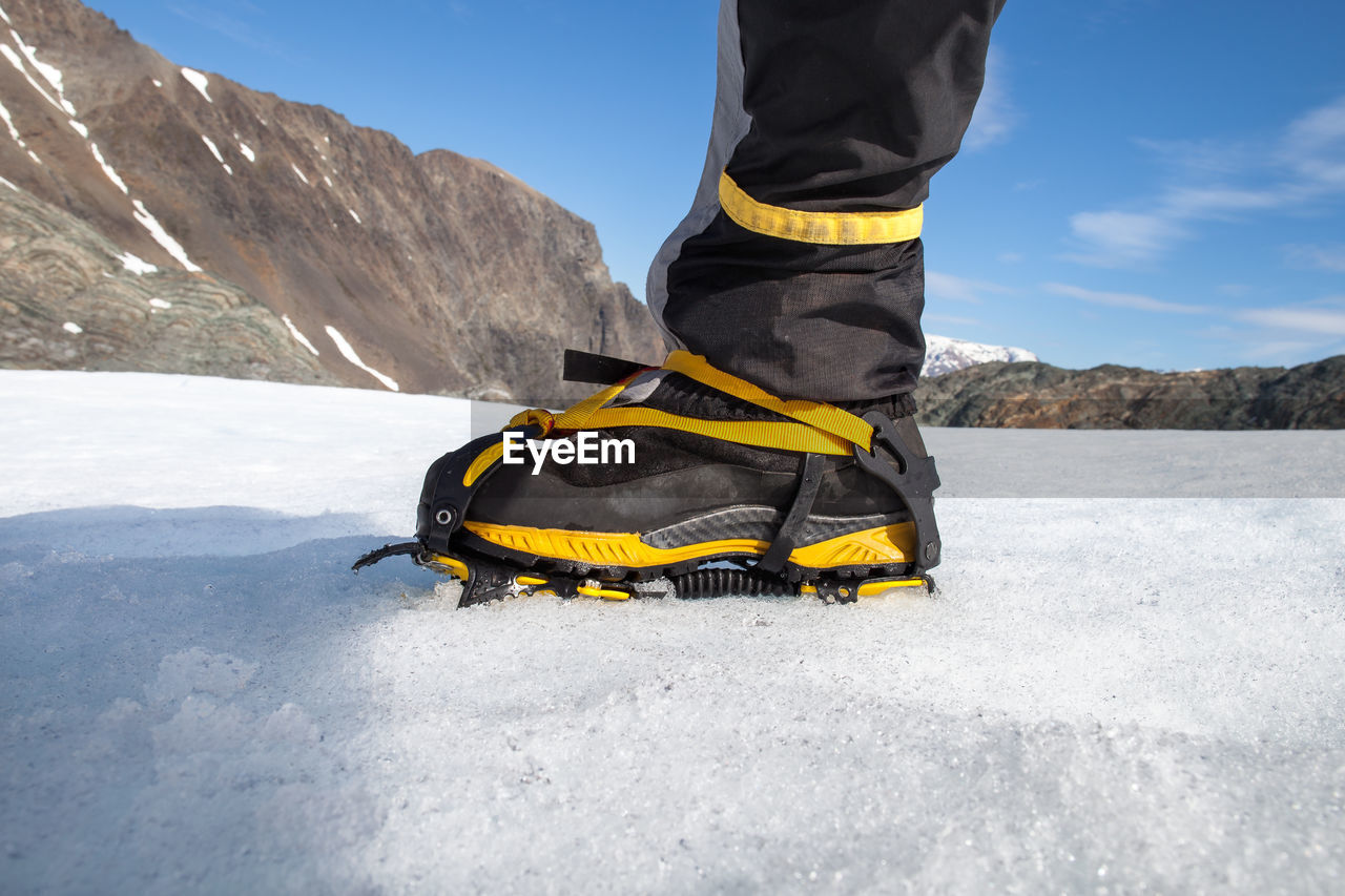 Low section of male hiker wearing crampon while ice climbing at lyngen alps