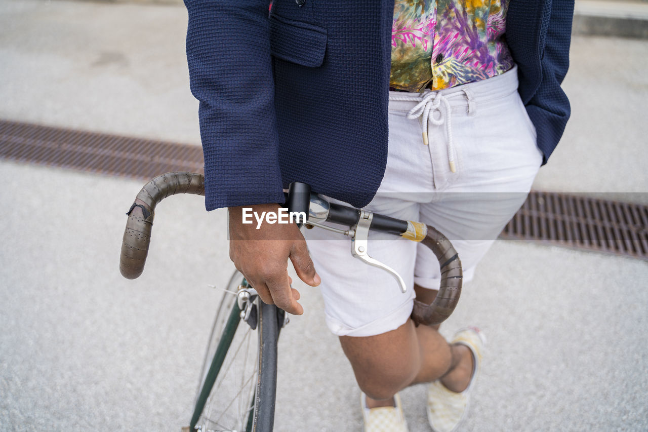 Close-up of stylish man leaning on bicycle