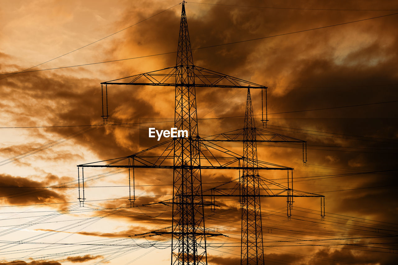 High voltage pylons for electricity and power against sky with dramatic clouds