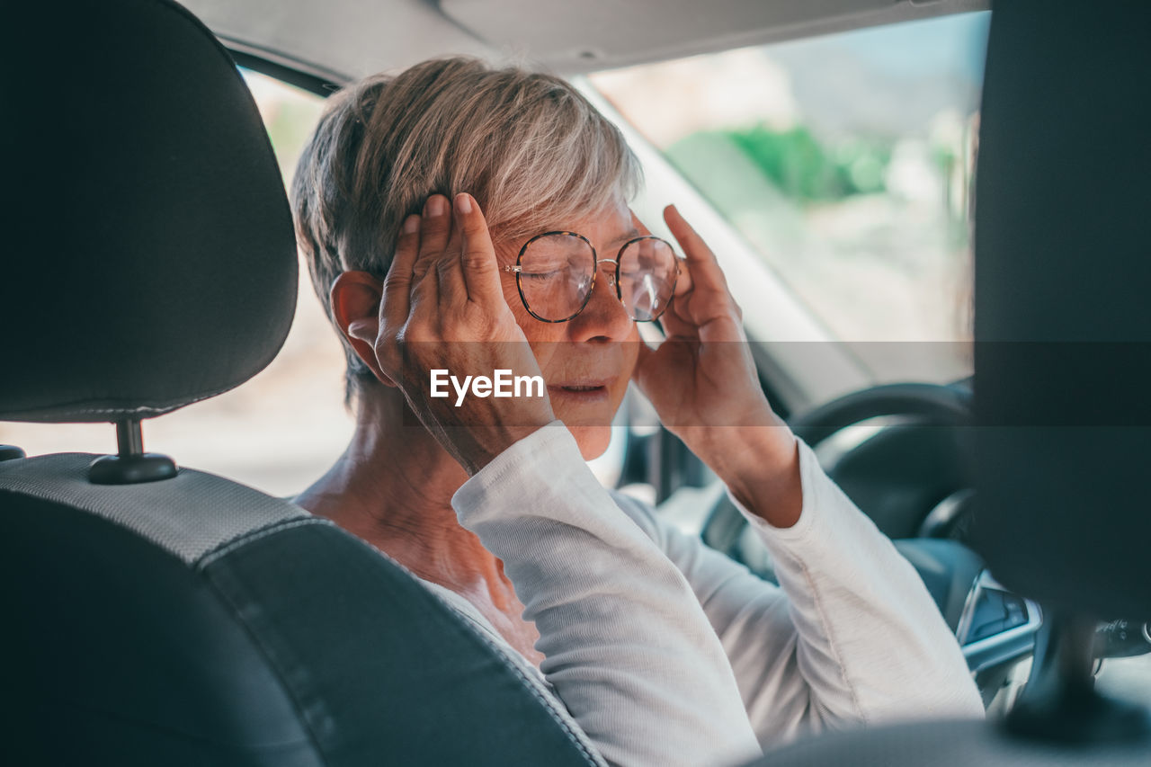 Senior woman wearing eyeglasses sitting in car