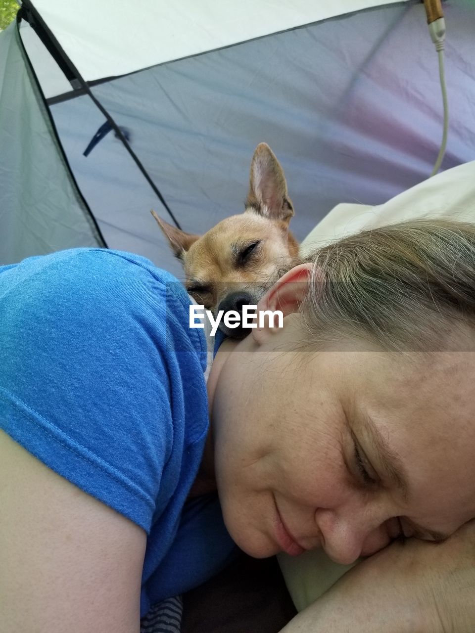 Close-up of mature woman and dog sleeping in tent 