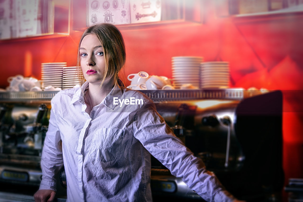 Portrait of young woman standing at cafe