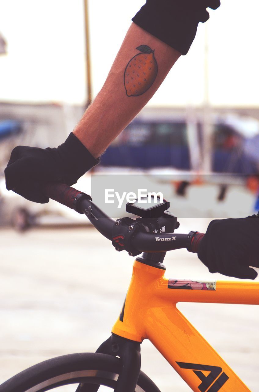 CLOSE-UP OF HAND HOLDING BICYCLE ON STREET