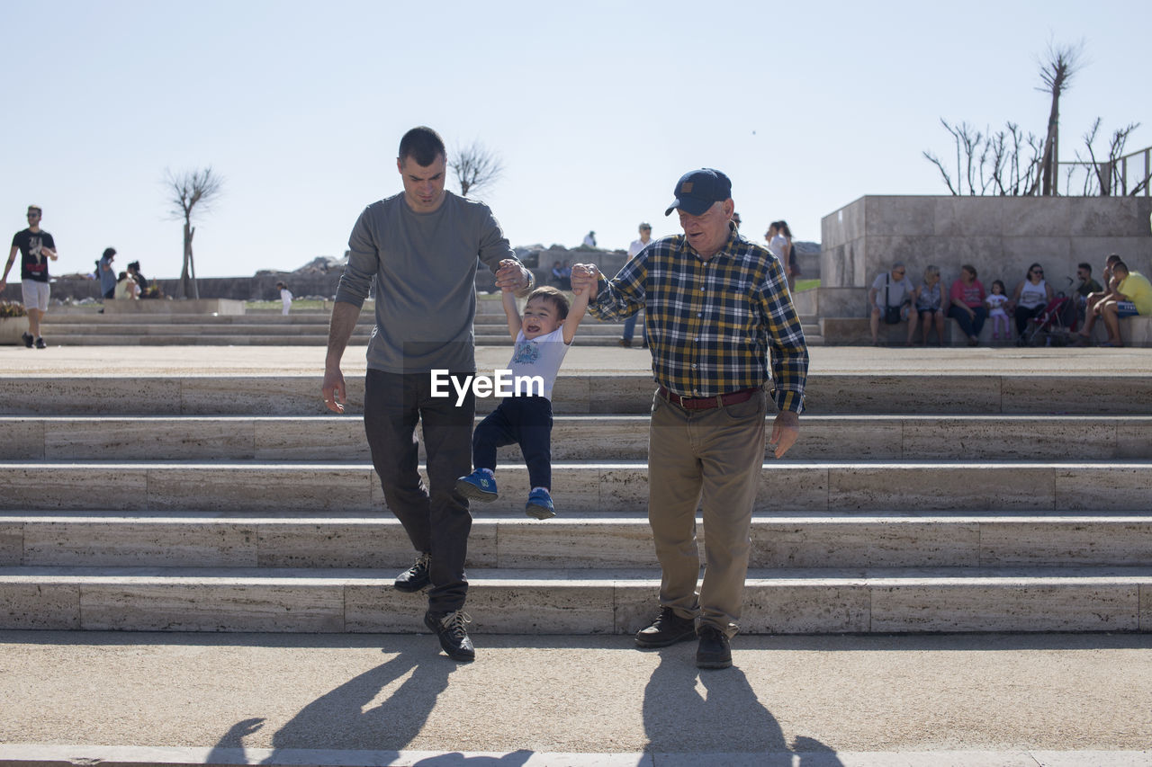 Parents carrying boy while walking on steps in city