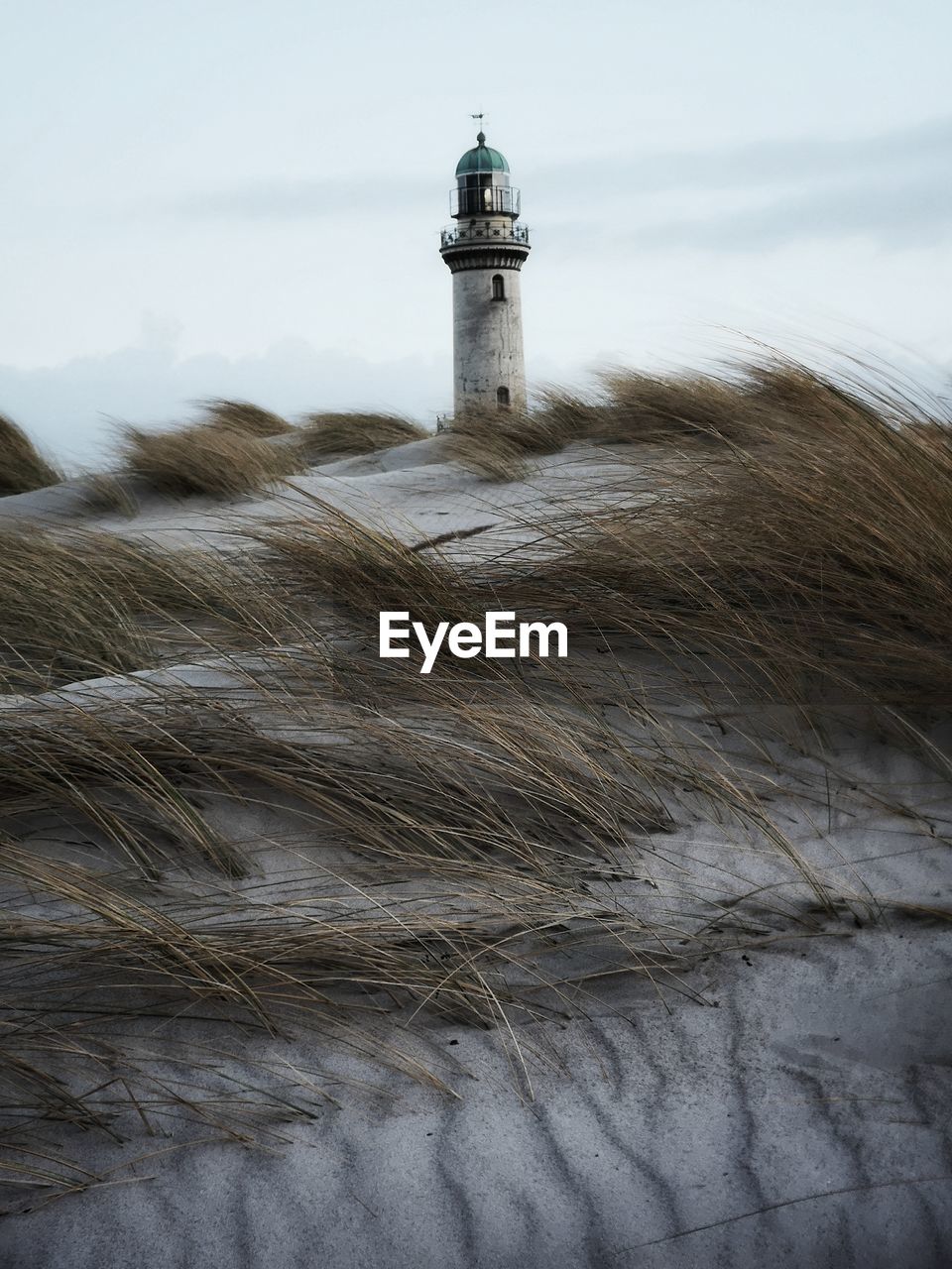 Lighthouse amidst buildings against sky