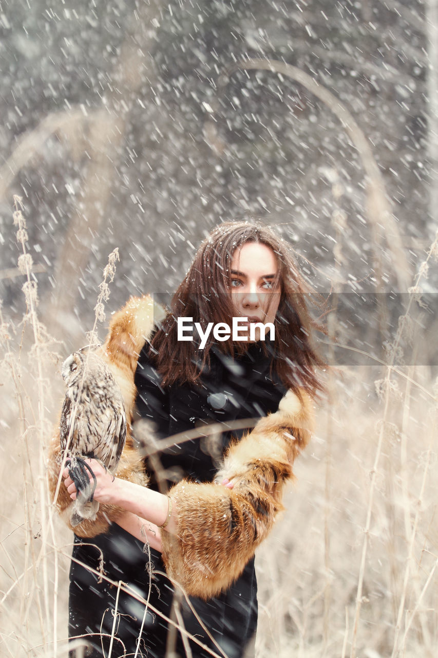 Young woman looking away standing outdoors during winter